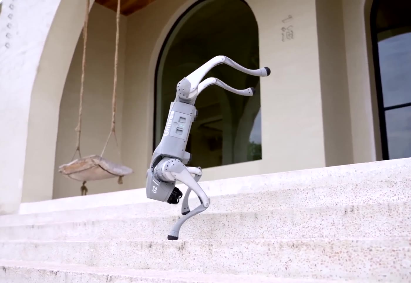 Unitree Go2 robot dog walking on its front legs up a flight of steps