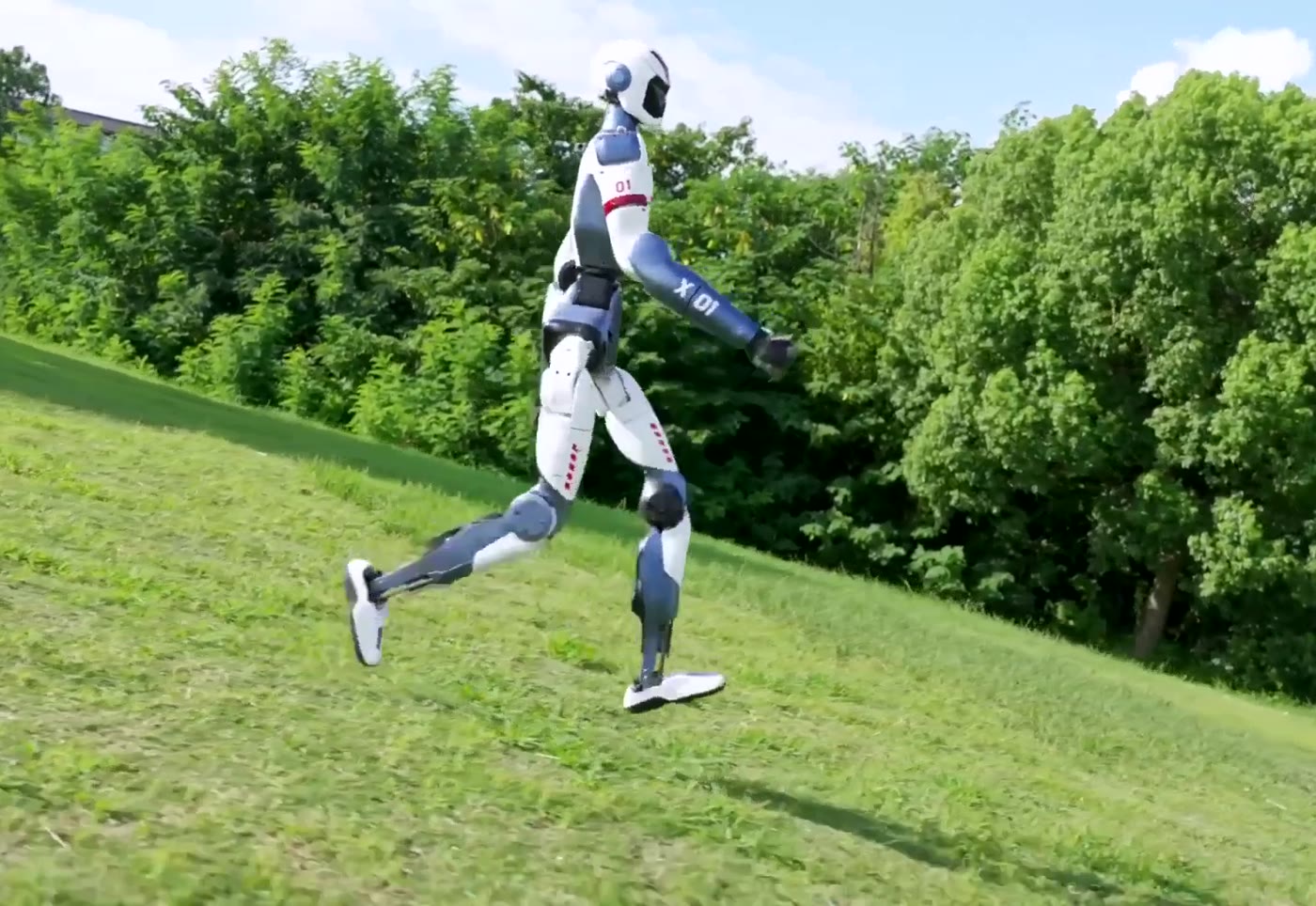 Unitree R1 humanoid robot running down a grassy hill
